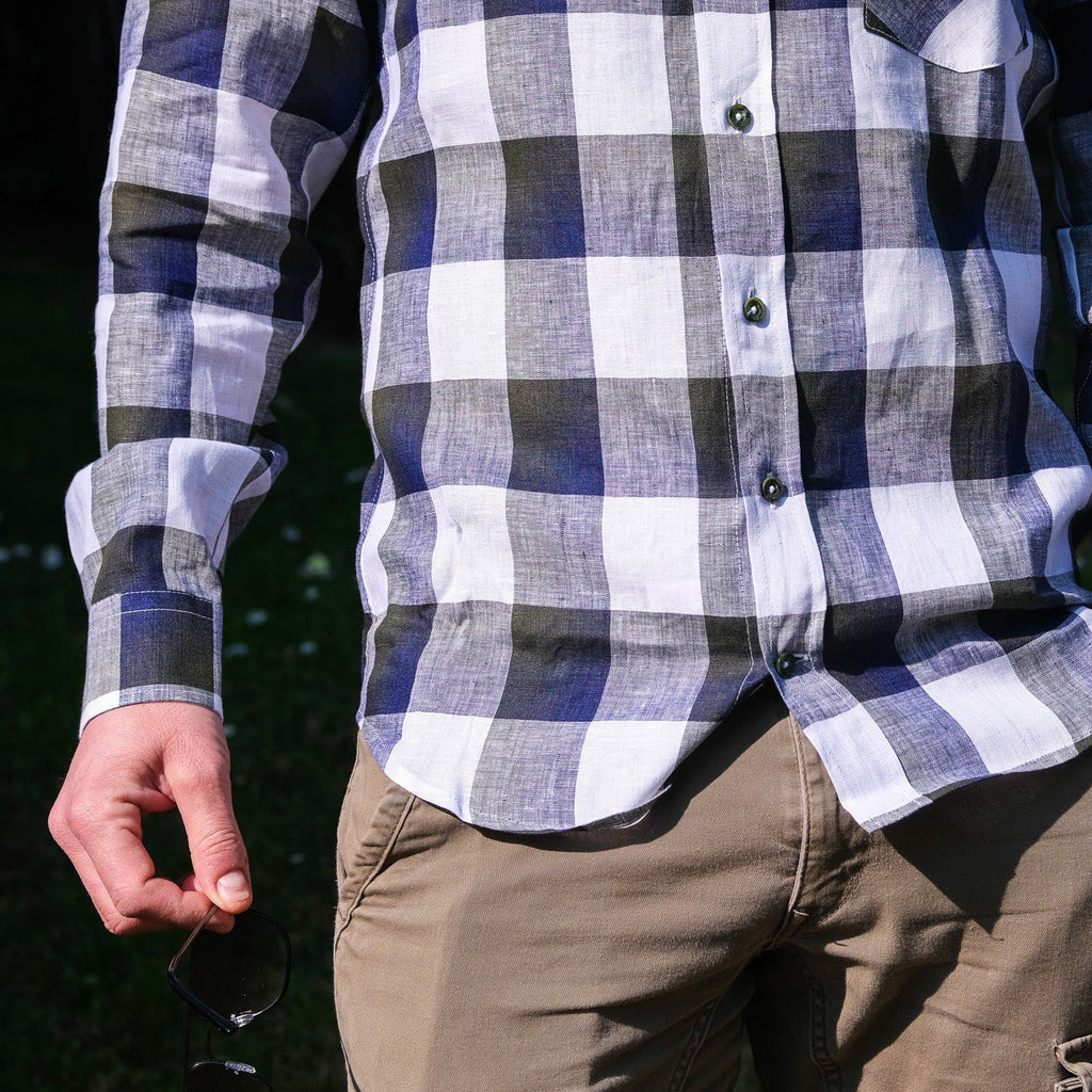Person wearing a plaid shirt and brown pants with a dark background
