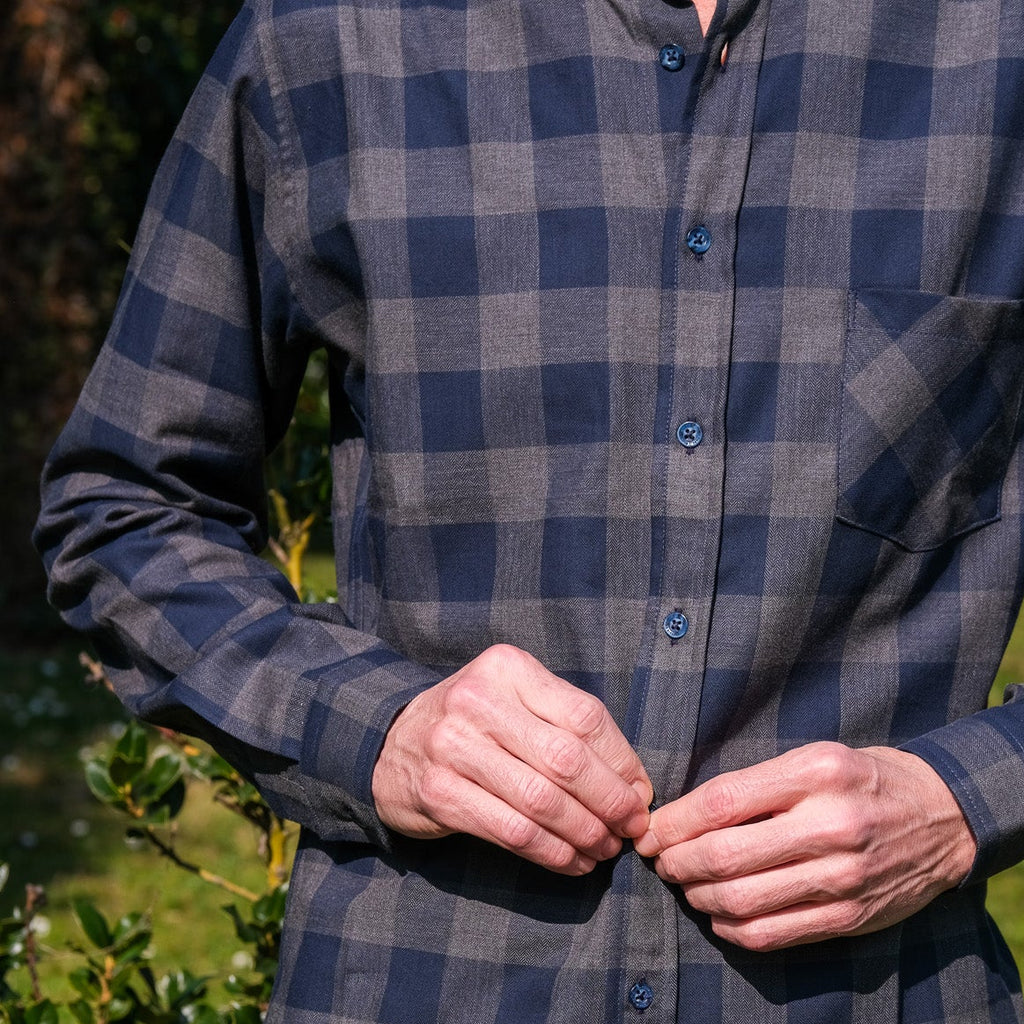 Person wearing a blue and gray plaid shirt outdoors